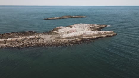 Aerial-pulling-back-shot-of-a-house-on-a-small-island-off-the-coast-of-Cohasset-4K