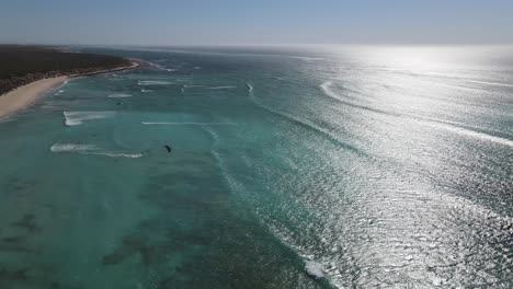Sobrevuelo-Aéreo-Océano-Cristalino-Con-Kite-Surf-Divirtiéndose-Durante-El-Día-Ventoso-Y-Soleado-En-Australia