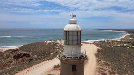 Aerial---Vlamingh-Head-Lighthouse-in-Pacific-Ocean,-Western-Australia,-close-to-town-and-blue-sky-and-clouds,-circling-orbit-shot