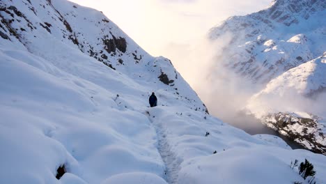 Mochilero-Solo,-Trekking-A-Través-De-Una-Gruesa-Capa-De-Nieve-Sobre-Las-Montañas-En-La-Pista-Routeburn