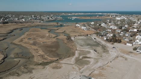 Aerial-flyby-shot-of-a-residential-neighborhood-and-the-salt-marshes-at-low-tide-in-Scituate,-MA