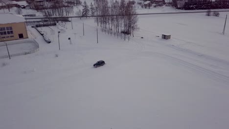 Black-SUV-Drives-Around-Snow-Field-with-Roll,-Making-Track-for-Skiing