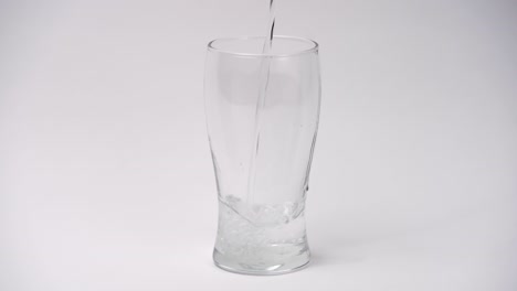 Close-up-and-slow-motion-of-pouring-water-into-glass-on-white-background