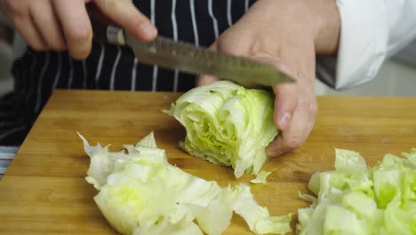 Cutting-green-fresh-cabbage-with-kitchen-knife-on-wooden-cut-board