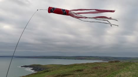 Paraglider's-windsock-waving-in-the-wind-with-cloudy-coastal-backdrop