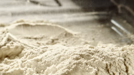 Close-up-of-wheat-flour-scattered-onto-pile-in-the-process-of-baking-bread