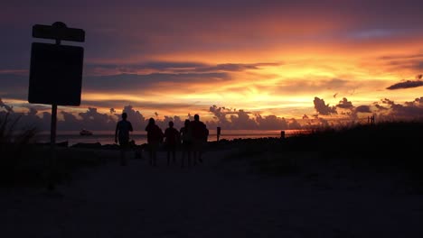 Silhouette-Von-Menschen,-Die-Einen-Spektakulären-Sonnenuntergang-Am-Strand-Genießen