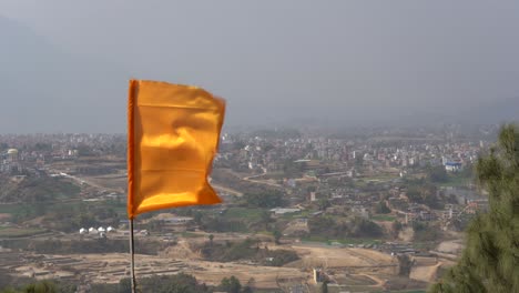 Una-Bandera-Hindú-Naranja-Ondeando-Al-Viento-En-Un-Templo-Con-Vistas-A-La-Ciudad-De-Katmandú,-Nepal