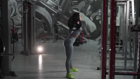 Contrasting-light-of-a-sporty-girl-squatting-with-a-barbell