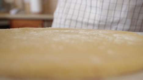 A-baker-sprinkles-flour-on-pastry-dough,-close-up-low-angle-view