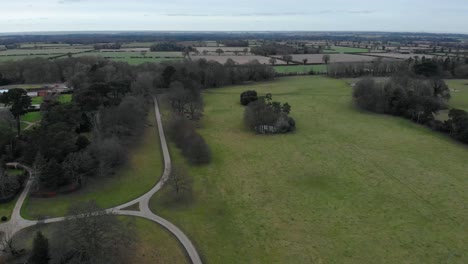 Aerial---Somerleyton-Hall-and-fields,-Somerleyton,-England,-wide-spinning-shot