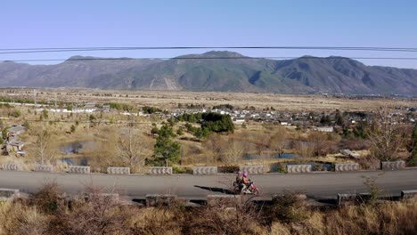Moped-scooter-driving-up-mountain-road-in-remote-China-countryside,-aerial-view