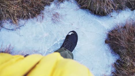 Pies-De-Personas-Pisando-Pantano-Congelado-Con-Hielo-Agrietado-Durante-El-Invierno-En-Noruega