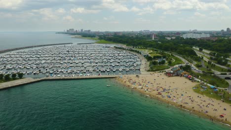 Aerial-View-of-Crowded-Beach-Next-to-Harbor-on-Lake-Michigan