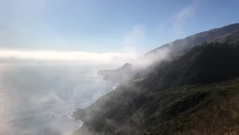 Sea-mist-rising-over-coastal-mountains,-summer-seascape-view