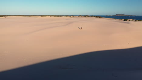 Hiker-walking-alone-on-the-Dark-Point-sand-dunes-at-Hawks-Nest,-New-South-Wales,-Australia