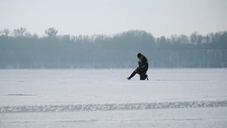 Silhouette-Fischer-Auf-Dem-Eis-An-Einem-Zugefrorenen-See-Im-Winter