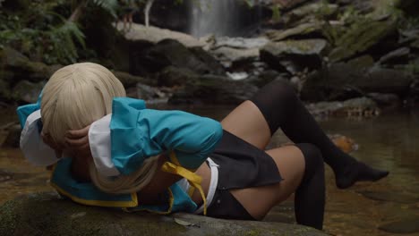 Sexy-anime-cosplayer-laying-on-a-rock-with-an-amazing-waterfall-in-the-background