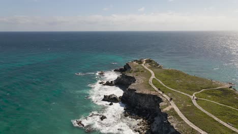 Aerial-of-rocky-cliffs-on-a-beautiful-blue-sea,-Isla-Mujeres,-Mexico