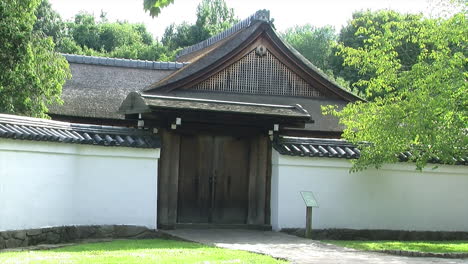 A-roofed-hinoki-wood-gate-and-tiled-wall-at-the-entrance-of-a-Japanese-house