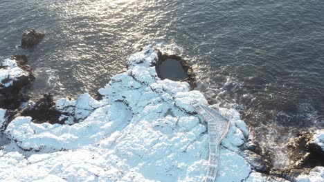Bright-sunlight-at-Brimketill-rock-pool-with-tourist-viewing-platform,-Iceland