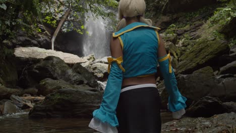 Beine-Eines-Anime-Cosplayer-Mädchens,-Während-Sie-Auf-Den-Fuß-Eines-Wasserfalls-Zugeht