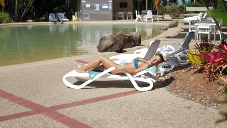Attraktive-Dame-Im-Sexy-Bikini,-Die-Im-Sommer-Auf-Einer-Sonnenliege-Am-Pool-In-Einem-Resort-Liegt