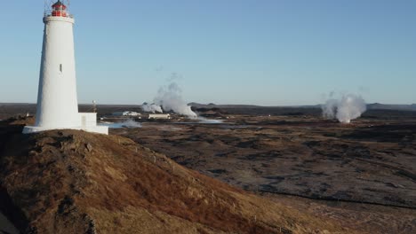 Island-Landschaft-Mit-Abgelegenem-Leuchtturm-Und-Geothermischem-Gas,-Das-Aus-Dem-Feld-Aufsteigt