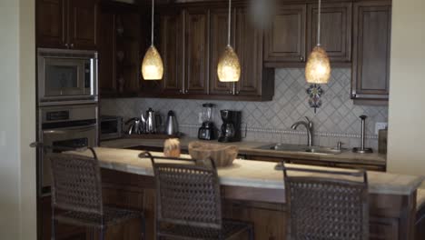 kitchen-with-wooden-furniture-next-to-microwave-oven,-bamboo-chairs-and-hanging-light-fixture