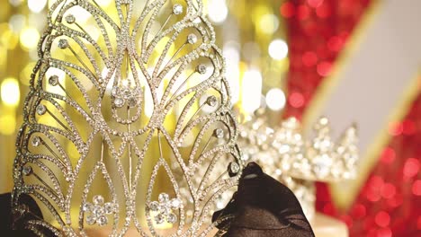 A-master-jeweler-checks-a-beauty-pageant-winner's-diamond-tiara---bokeh-blurred-background-with-gown-and-sash