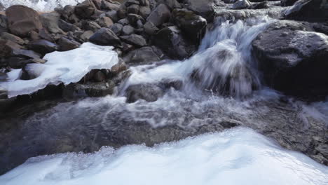 Wasser,-Das-Auf-Dem-Fluss-Mit-Eis-Auf-Den-Felsen-Im-Wasserfall-Grundarfoss,-Island,-Herunterläuft