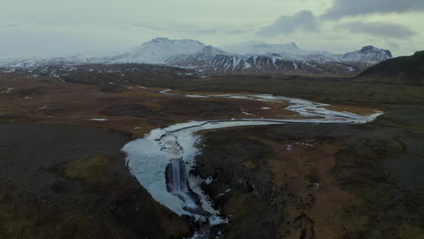 Aerial-View-Of-Svodufoss-Waterfall-And-Snaefellsjokull-Stratovolcano-At-Winter-In-Iceland