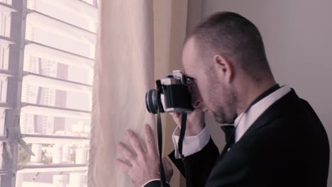 Man-spying-from-a-window-and-taking-pictures