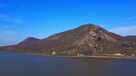 Aerial-drone-footage-approaching-the-Appalachian-mountains-over-a-river-in-new-york's-hudson-valley-during-early-spring-at-breakneck-ridge-and-the-hudson-river