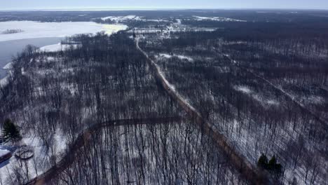 Aerial-shot-moving-forward-over-a-forest-in-winter-following-a-car-on-the-road