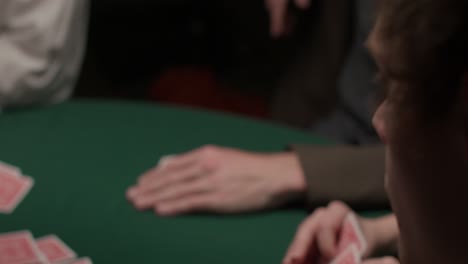Spieler,-Der-Zwei-Karten-In-Einem-Dunklen,-Stimmungsvollen-Casino-über-Seine-Schulter-Zieht