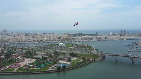 UAE-FLAG:-Top-view-of-the-Flag-of-the-United-Arab-Emirates-waving-in-the-air-over-Sharjah's-Flag-Island,-Sharjah-city,-UAE-National-Day,-4K-Video