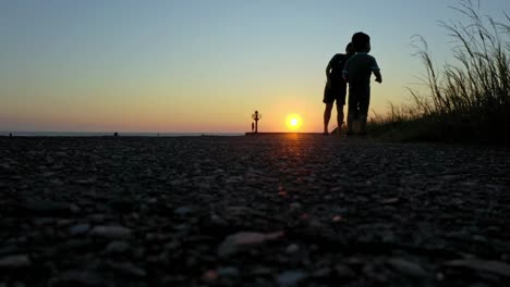 Low-angle-shot-showing-silhouette-of-kids-playing-at-beach-during-sunset-in-Taiwan