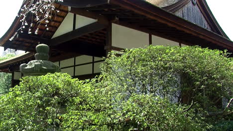 Camera-jibs-up-from-view-of-stone-pathway-to-Japanese-house-and-blossom-laden-cherry-tree-branches