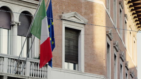 Italian-and-European-Union-flags-in-Ferrara,-Italy,-UNESCO-World-Heritage-Site