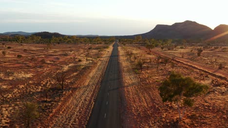 Luftaufnahme-Der-Outback-Road-Mitten-In-Der-Wüste-Bei-Sonnenuntergang-In-Der-Nähe-Von-Alice-Springs-Town-In-Australien