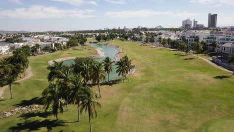 Aerial-view-of-a-golf-course-with-artificial-lagoon-and-palm-trees,-Mexico