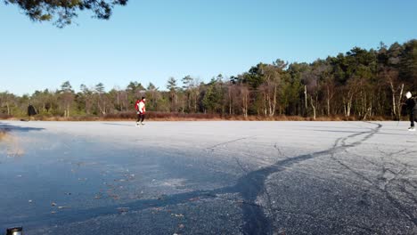 Ice-Skaters-Skating-On-A-Frozen-Lake-Covered-In-Ice-And-Snow-In-Winter