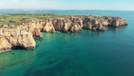 Distant-view-of-the-Ponta-da-Piedade-lighthouse-and-cliffs-overlooking-Atlantic-ocean,-Lagos-,-Algarve