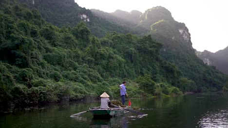 Slow-motion-shot-of-traditional-Vietnamese-vessel-In-magical-lake-landscape,-Ninh-Binh