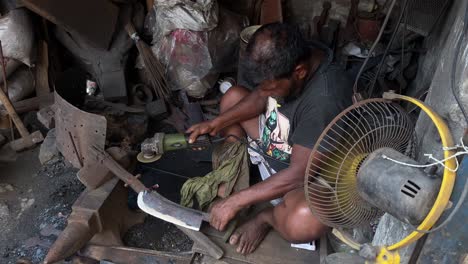 Schmied-Arbeiter-Schärfen-Messer-Vom-Winkelschleifer-Im-Eisengeschäft-In-Dhaka,-Bangladesch