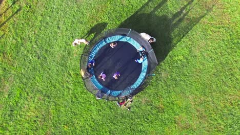 Group-of-kids-jumping-on-trampoline-during-vacation-trip-on-farm-during-summer