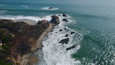 Overhead-aerial-view-of-waves-crashing-against-the-rocky-coast-of-Punta-Zicatela