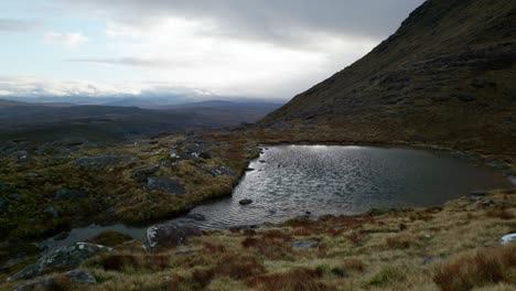 wind-blows-ripples-across-a-small-lochan-in-teh-highlands-of-Scotland-under-a-dark,-moody-sky