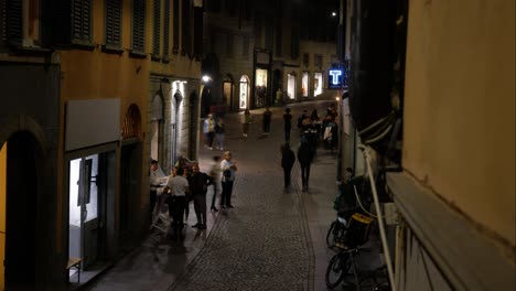 People-walking-in-narrow-night-old-town-street-of-Bergamo,-time-lapse-view